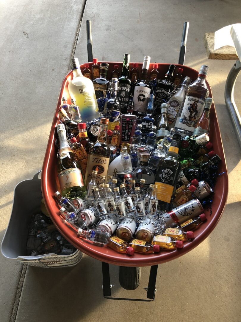A red wheelbarrow filled with assorted bottles and jars.