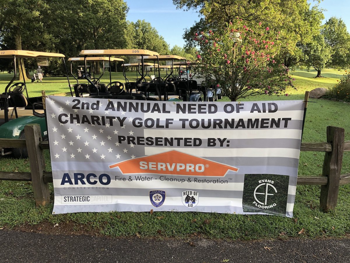 Banner for the 2nd Annual Need of Aid Charity Golf Tournament outdoors.