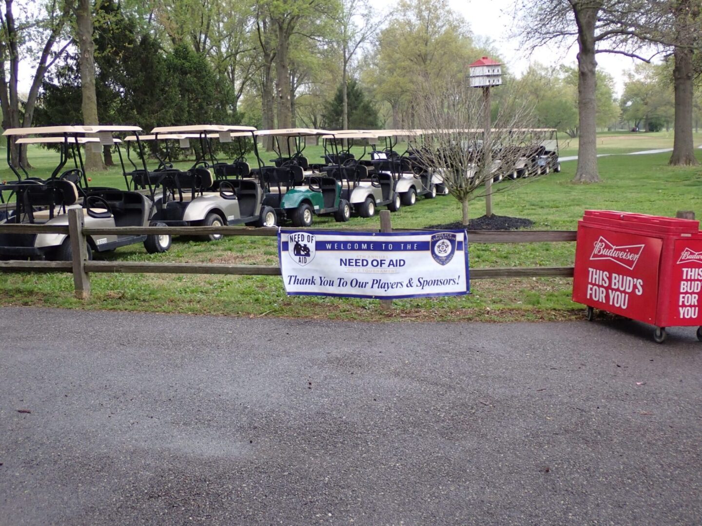 Golf carts lined up behind a banner for a golf tournament event.