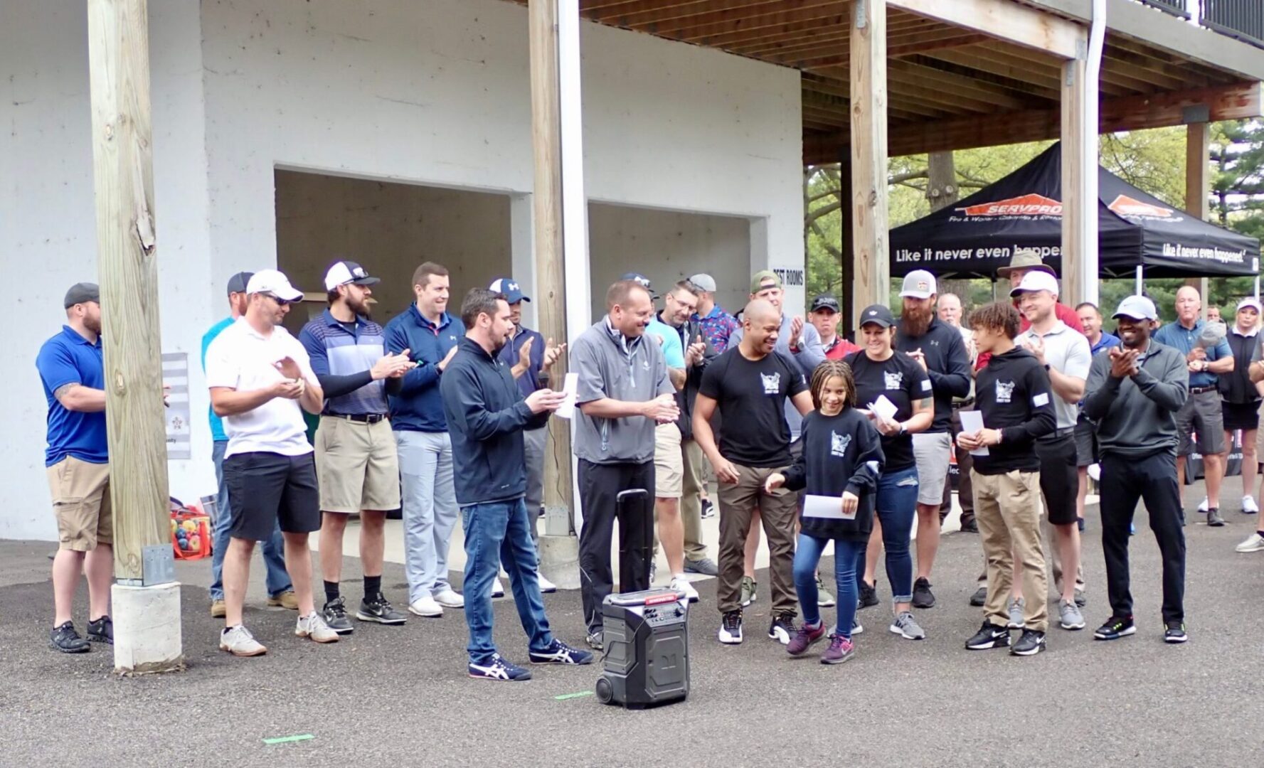 Group of men standing outdoors, engaging in a casual gathering or event.
