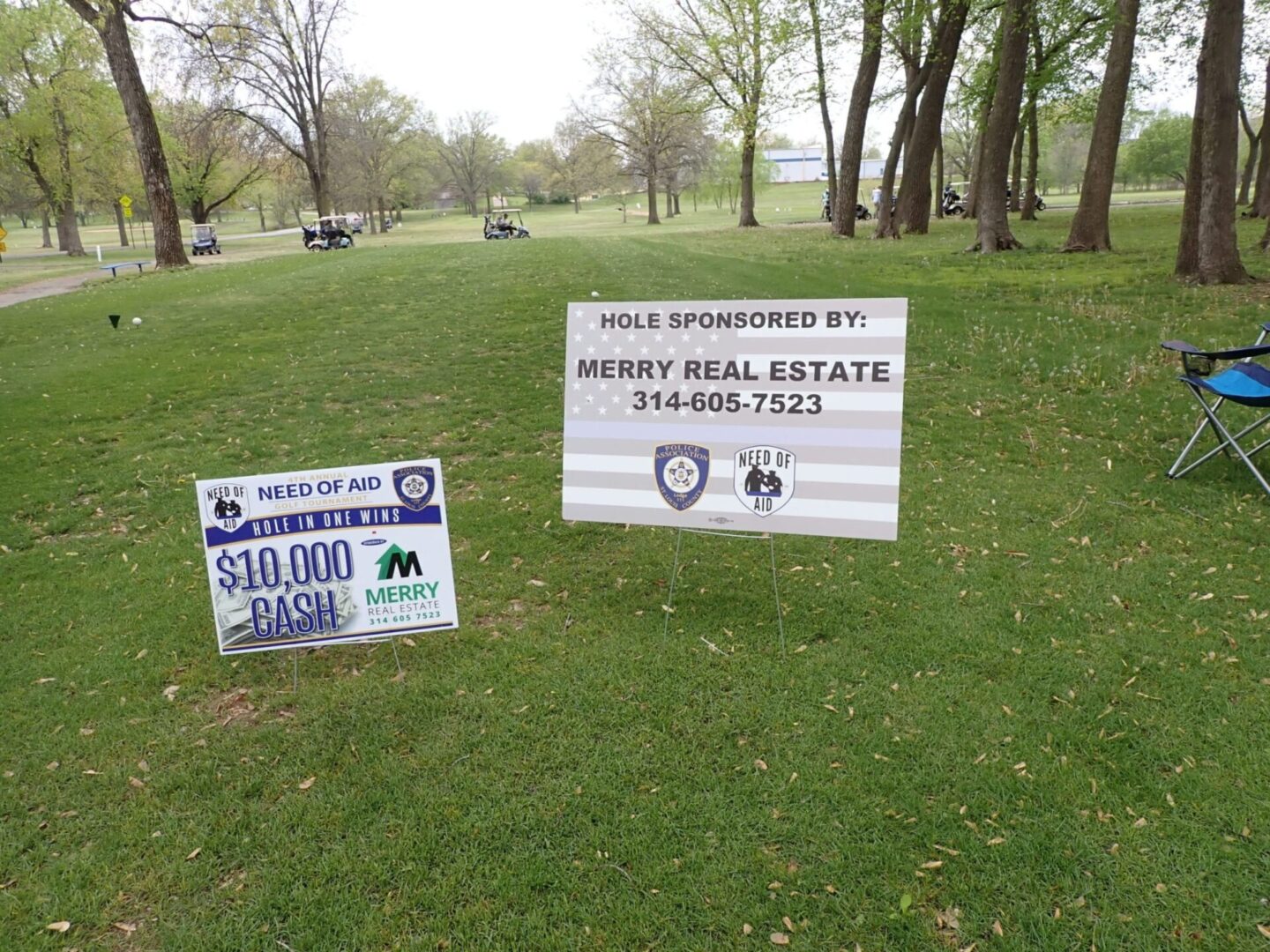 Signs promoting real estate services and a contest in a park area.
