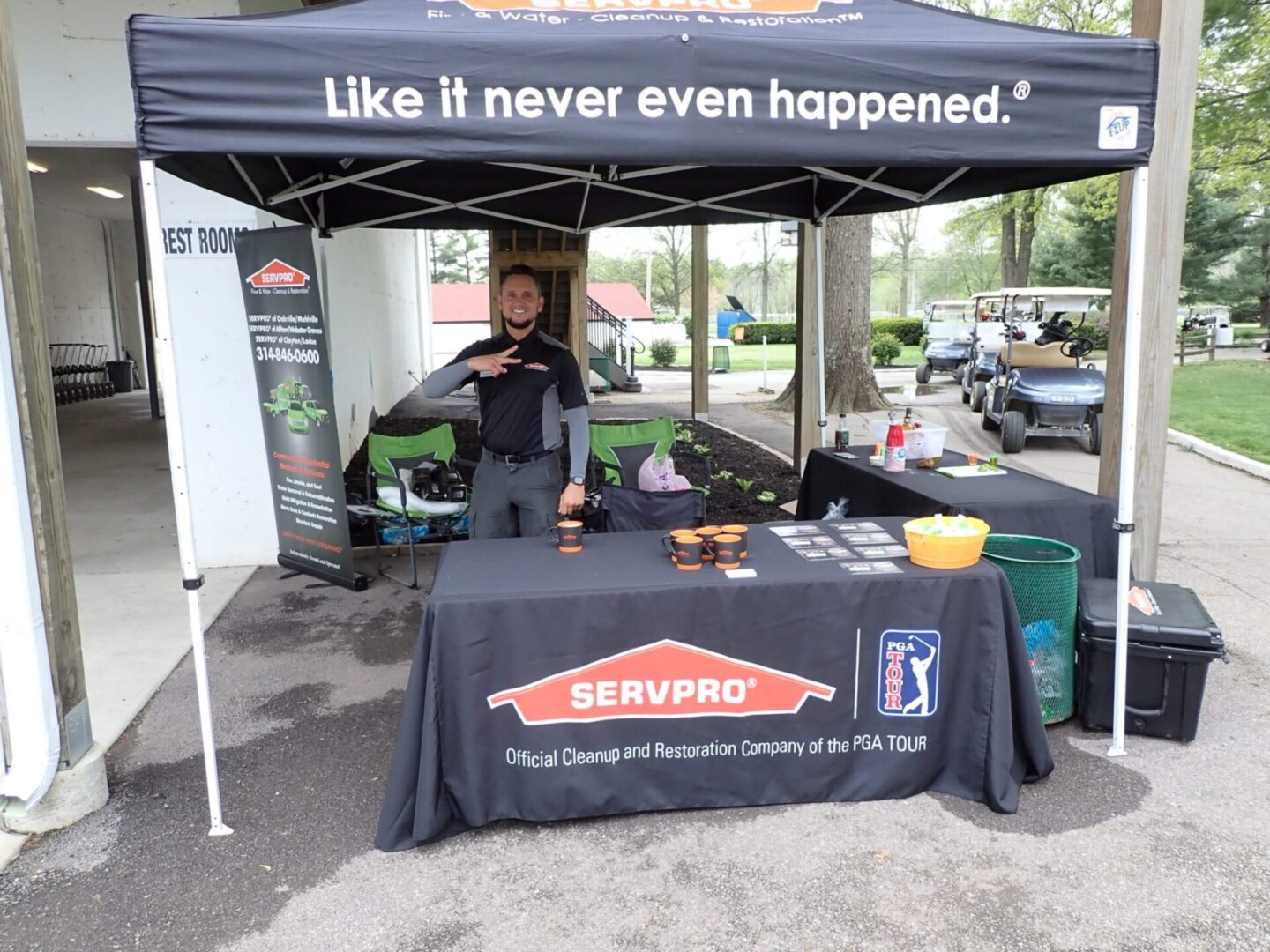 A man stands behind a SERVPRO booth with a canopy and promotional materials.