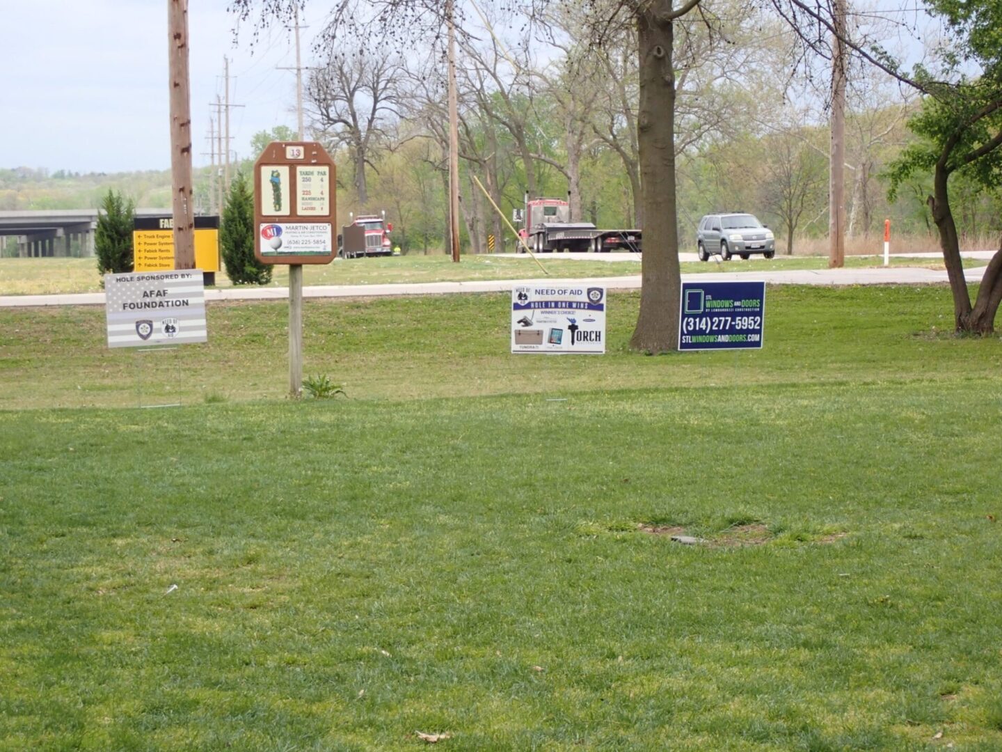Golf course with signs advertising lessons and events on a grassy area.