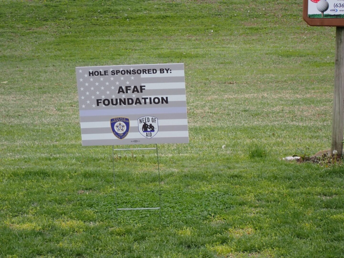 A white sign on grass promoting the AFAF Foundation and a sale event.