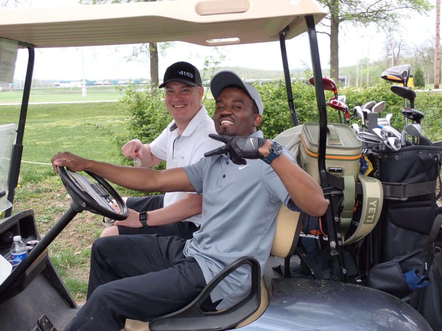 Two men enjoying a golf cart ride on a sunny day.