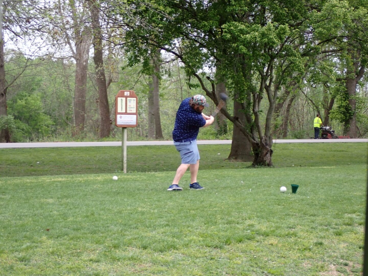 A person is about to hit a golf ball on a green course.