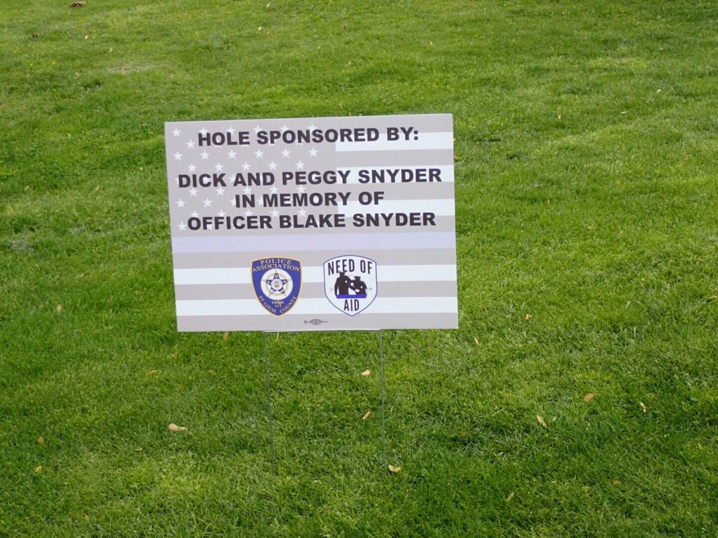 Memorial sign for Dick and Peggy Snyder at a golf hole.