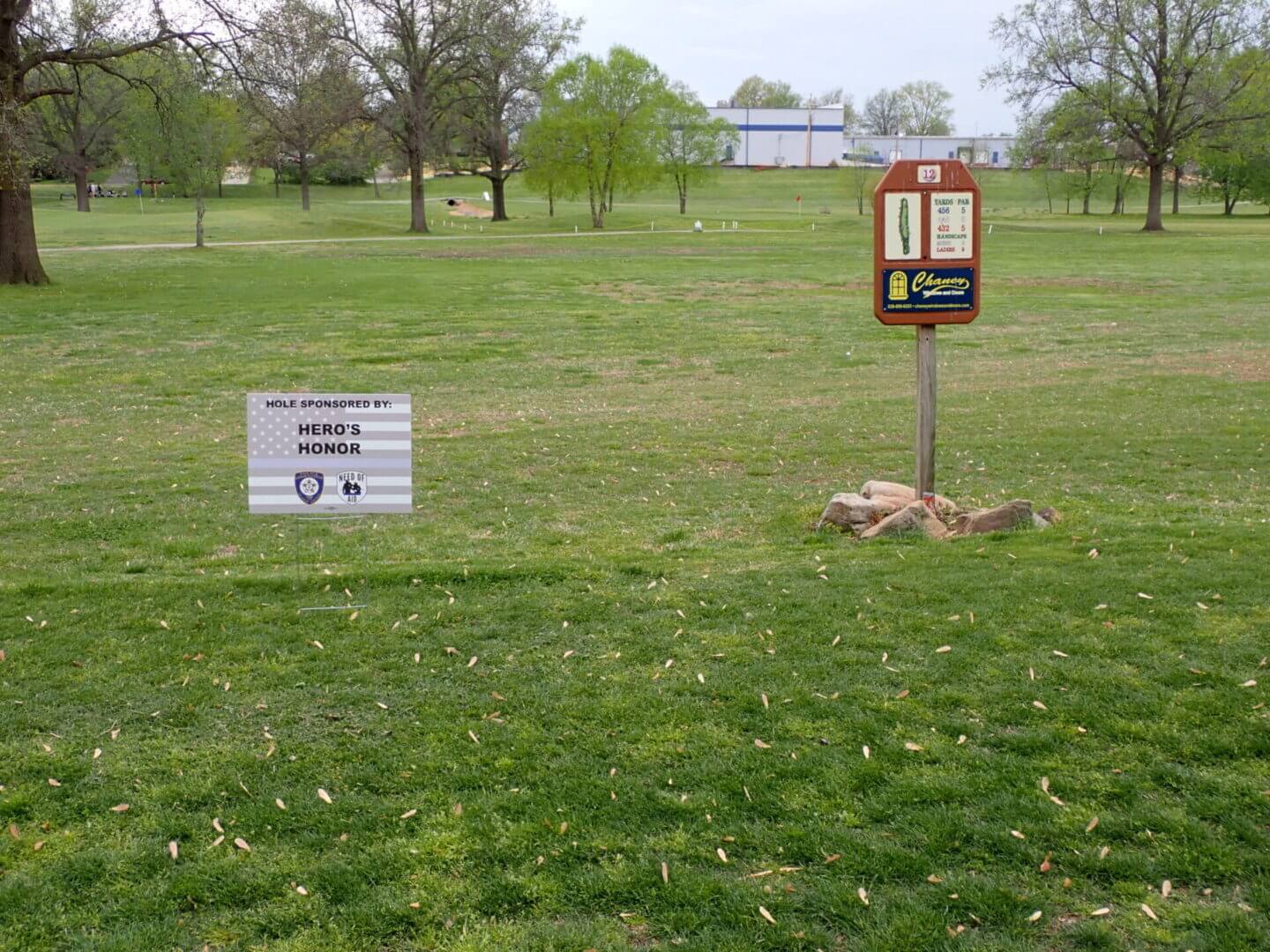 Disc golf baskets and signs in a grassy park area.