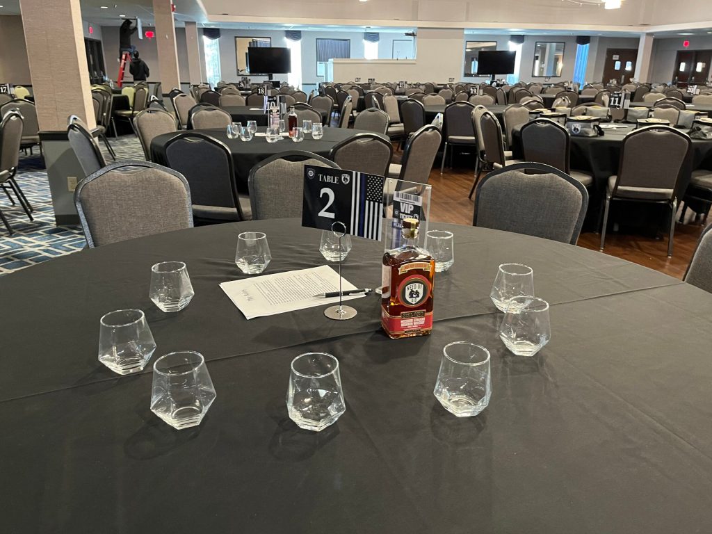 Round table set for six with glasses and a number two sign in a banquet hall.