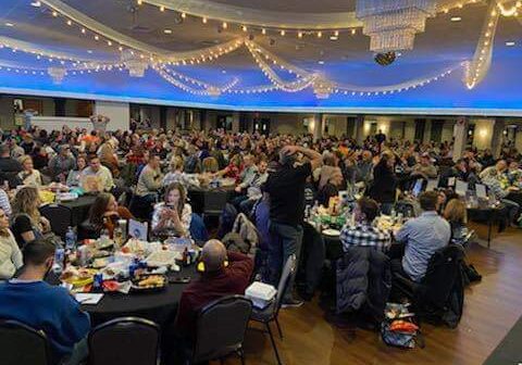 A large group attends a formal banquet in a decorated hall.