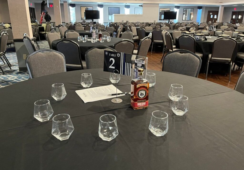 A round table set with glasses and a menu in a banquet hall.